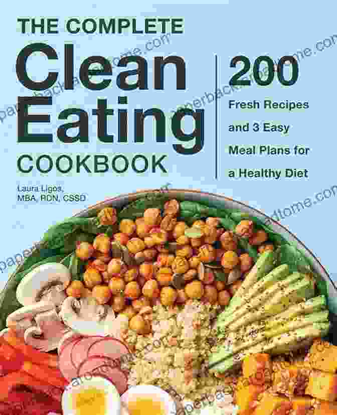 A Woman Holding A Copy Of 'The Must Have Clean Eating Cookbook In The Kitchen.' The Must Have Clean Eating Cookbook In The Kitchen :1000 Days Healthy Recipes And 4 Week Meal Plans To Help You Living Health